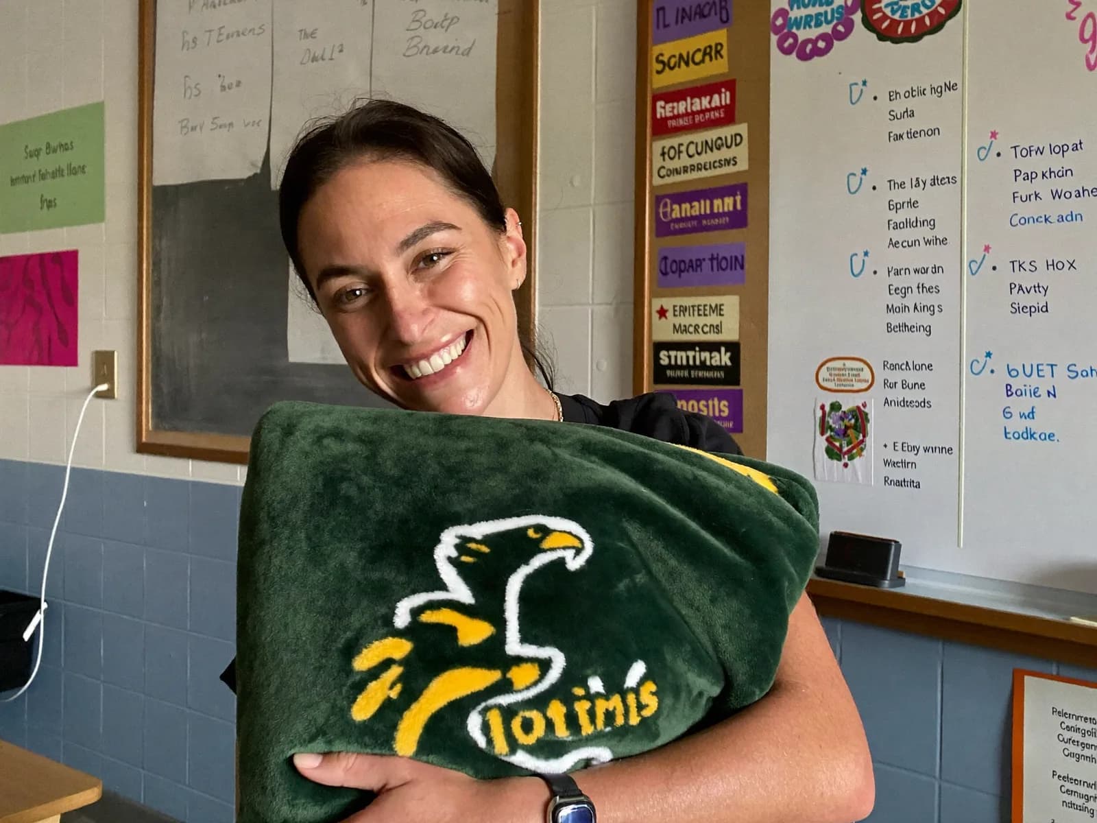 Teacher in her classroom hugging her school's free custom sample blanket